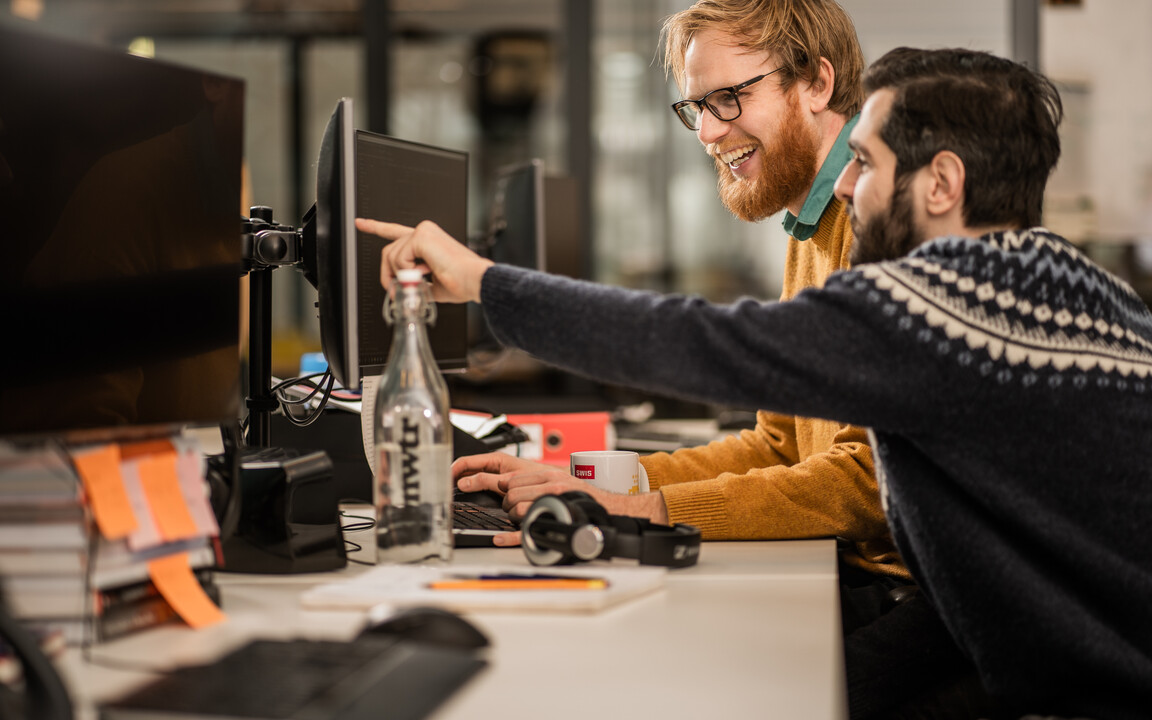 Twee SWIS'ers werken samen achter een computer.