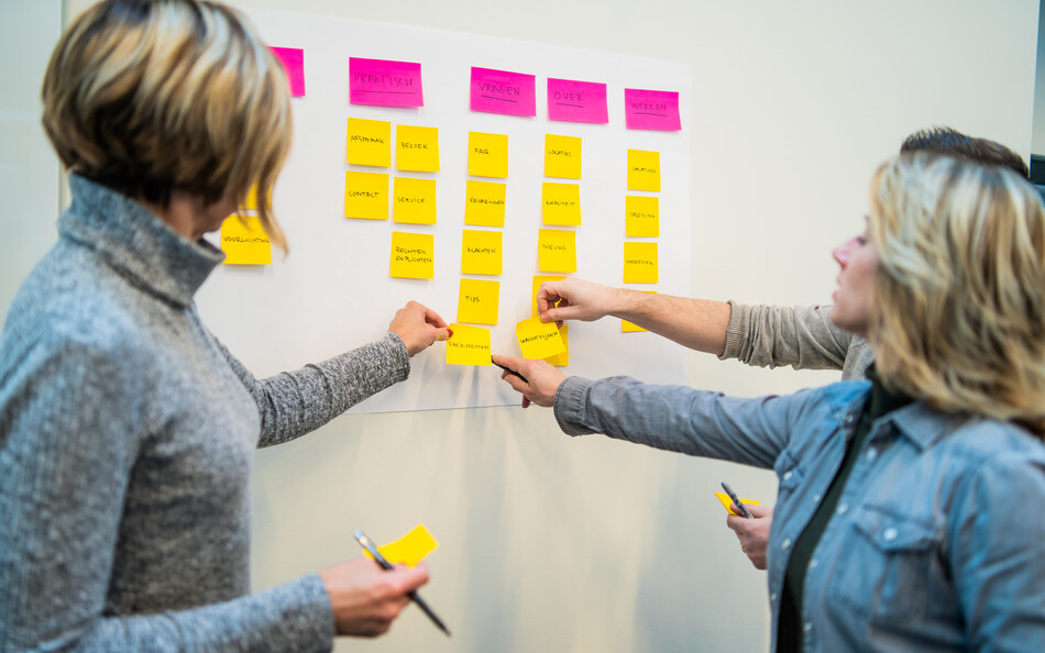 Foto van klanten die post-it's plakken tijdens een Strategische Sessie