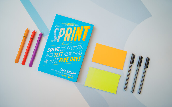 Foto van het boek Sprint op een tafel met pennen en post-it's er omheen