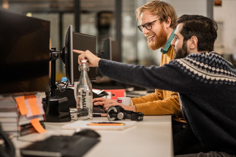 Twee SWIS'ers werken samen achter een computer.