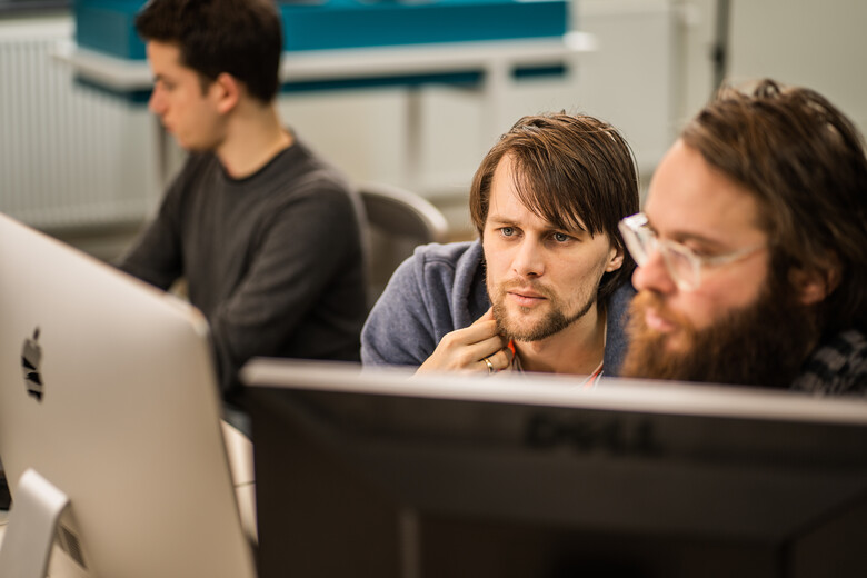 Twee SWIS'ers werken samen achter een computer.