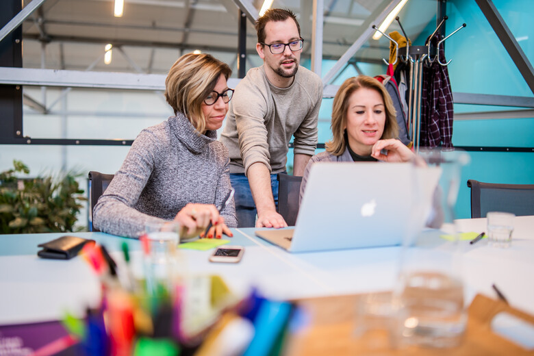 Man en twee vrouwen kijkend naar laptop